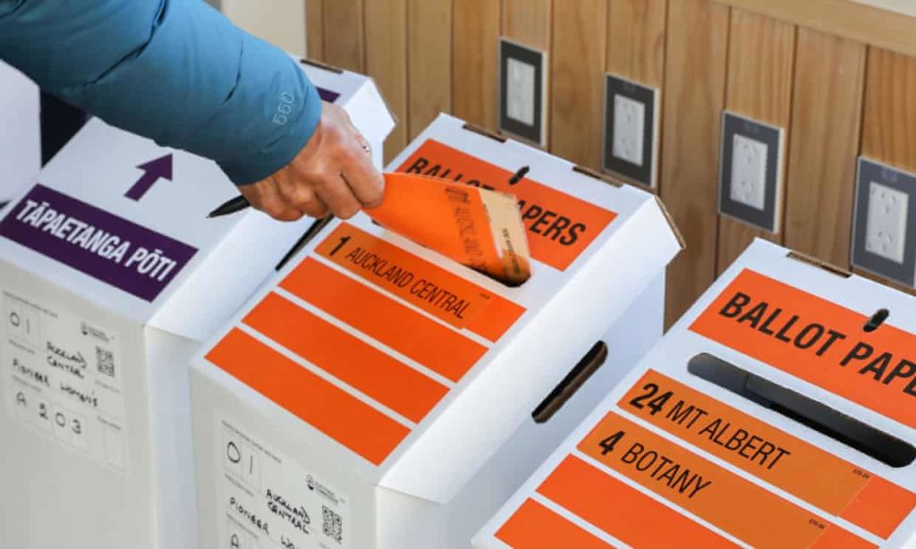 Élection en Nouvelle Zélande: une main dépose un bulletin dans une urne en carton.